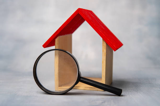 istock Magnifying glass in front of a miniature house. 2161487615
