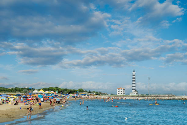 A picturesque view of a stone pier extending into the turquoise sea. Gentle waves touch the coastal rocks, while the horizon blends seamlessly with the cloudless blue sky. In the distance, a few people stand at the edge of the jetty, enjoying the serene seascape. A calm and peaceful atmosphere, evoking a sense of freedom and tranquility. A perfect conceptual image for travel, nature, or inspirational themes.