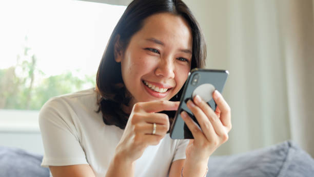 istock close up young asian woman use smartphone and looking on device screen for check notification or read news or alert from application in living room at home for people lifestyle and technology concept 2161490462
