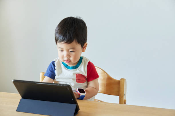 istock Little boy using laptop and smart watch at table in house 2161490761