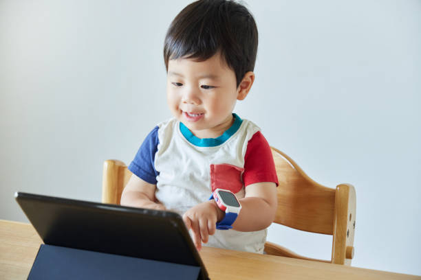 istock Little boy using laptop and smart watch at table in house 2161490762