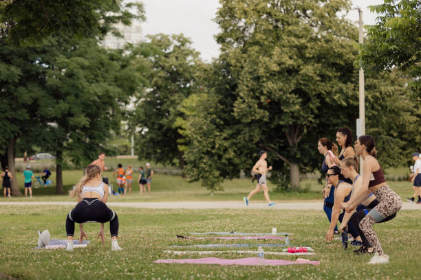 Group of strong young men with naked torsos takes part in morning workout at outdoors gym in a public park. Shooting in summer sunny morning