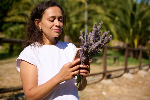 istock Woman enjoying nature while holding a lavender bouquet and using smartphone on a sunny day 2161495876