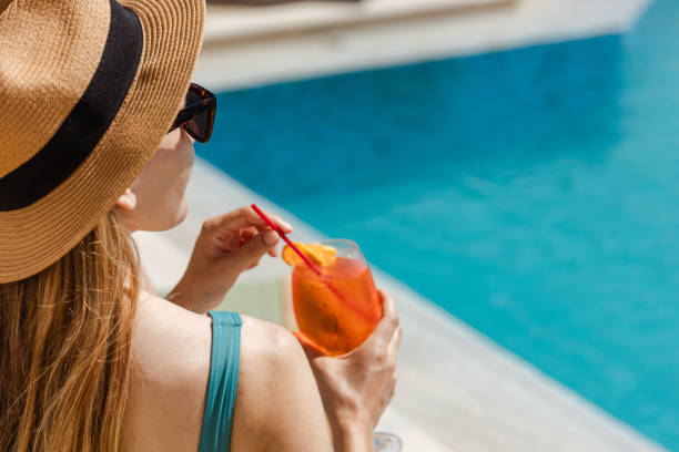 istock Woman relaxing at poolside with cocktail and sun hat 2161505566