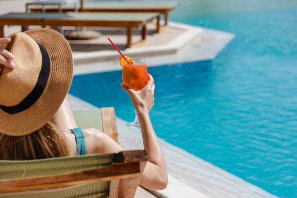 istock Woman relaxing by pool with cocktail on a sunny day 2161505567