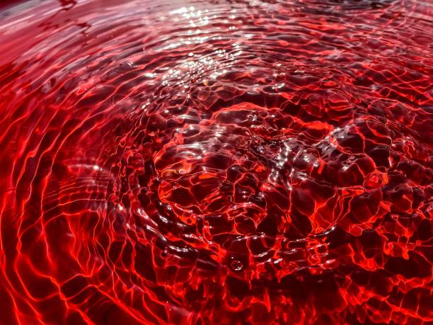 istock Close-up rain drips on a red background and leaves circles on the water. 2161507459