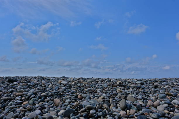 Sea pebbles and blue sky with white clouds on the beach