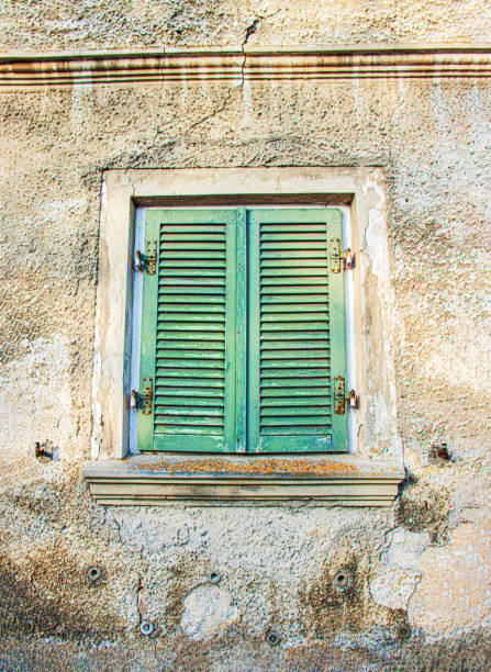 closed window with green wooden shutters, an old stone wall, dysfunctional area, ghetto