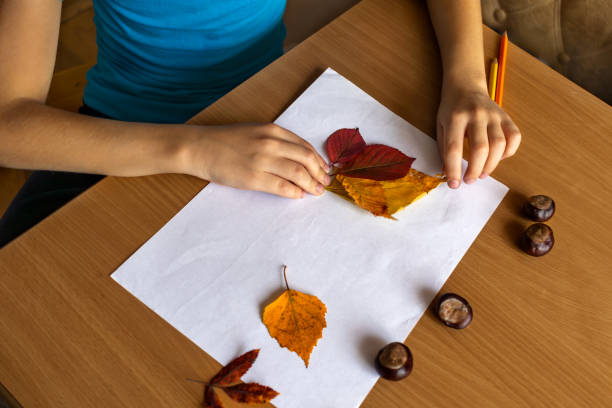 istock Autumn creativity. Child makes a craft from fallen leaves. Hands in close-up. Handwork 2161510513
