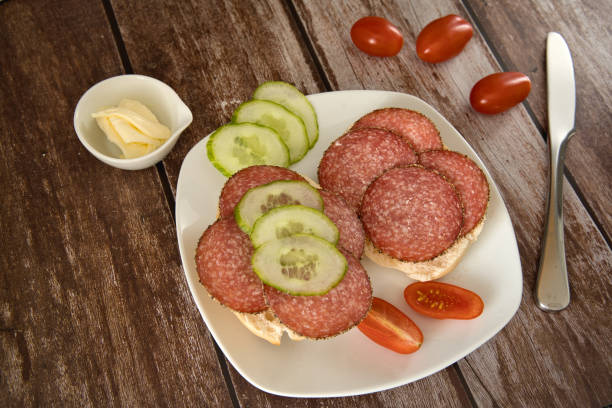 2 rolls with cheese and salami on a plate with tomatoes