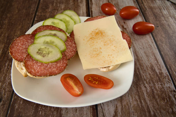 2 rolls with cheese and salami on a plate with tomatoes