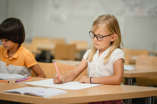 Young girl student do tasks and write on notebook on the class