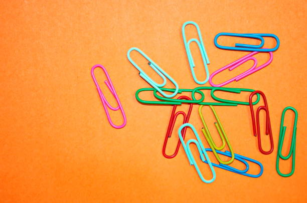 Multicolor paper clips on orange background Stationery for school or business Copy space Blanc for notes