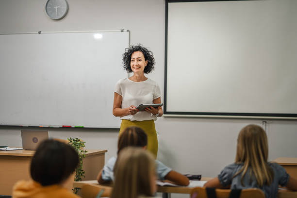 istock Mature teacher teach a lesson young students and hold tablet 2161516070