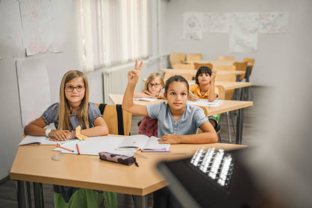 istock Young girl student raise his hand to answer a question during a lesson 2161516521