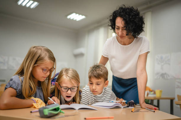 istock Mature teacher check how her young students do tasks on the class 2161517448