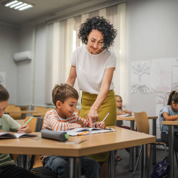 istock Mature teacher check how her young students do tasks on the class 2161517460