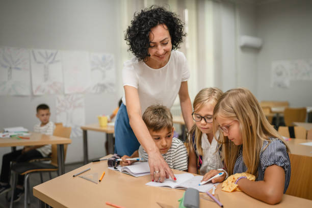 istock Mature teacher check how her young students do tasks on the class 2161517535