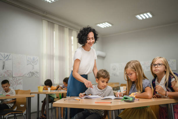 istock Mature teacher check how her young students do tasks on the class 2161517541