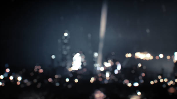 A blurry image of city lights and a fireworks display. The lights are out of focus, creating a bokeh effect. The fireworks appear as streaks of light against the dark sky.