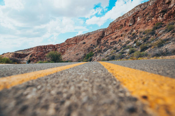 Low angle views of the center of a road with a cliff in the background
