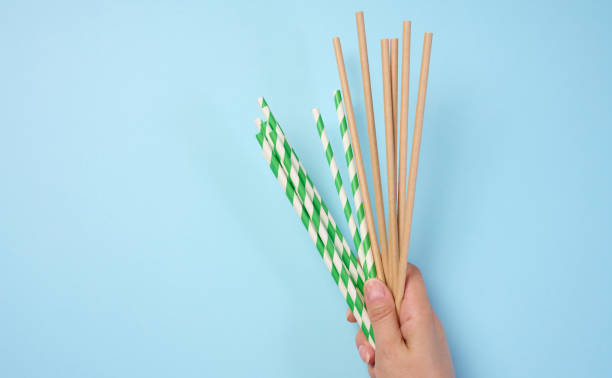istock Female hand holding paper cocktail straws on a blue background 2161528095