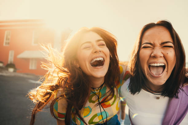 istock Two friends laughing and posing outdoors enjoying a sunny day 2161532457