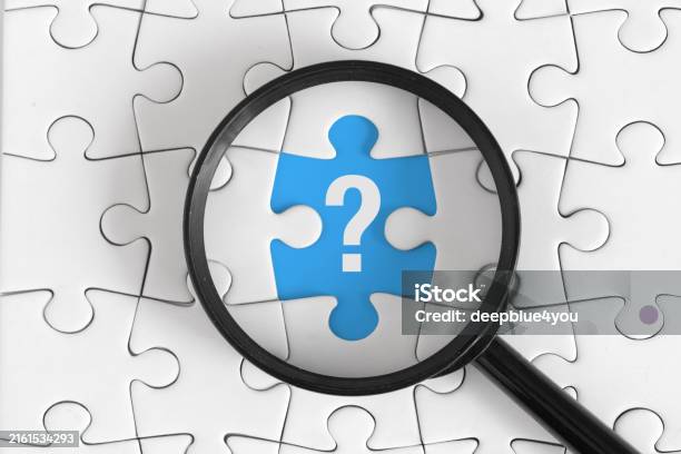 White Puzzle With Black Magnifying Glass And White Question Mark On Blue Piece Top View Stock Photo - Download Image Now
