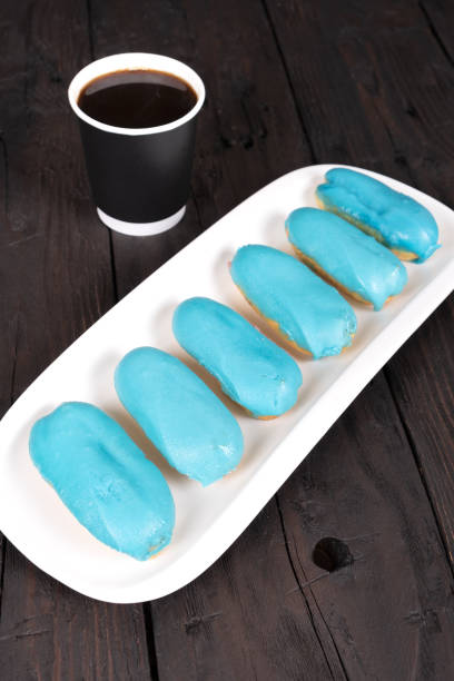 Delicate Eclairs with Blue Frosting and a Cup of Coffee, a Delightful Afternoon Treat
