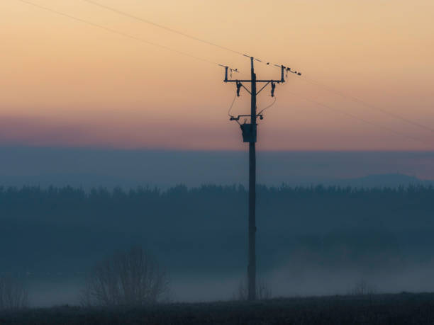Powerline and farm fence in silhouette at sunrise rural Victoria