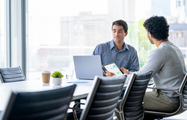 istock Two businessmen working on a digital tablet and laptop computer in the office a board room or meeting room. 2161538523
