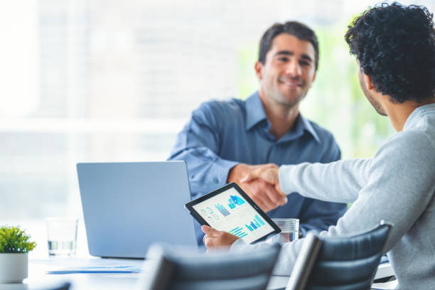istock Two businessmen working on a digital tablet and laptop computer in the office in a board room or meeting room 2161538564