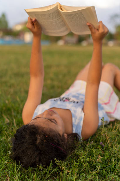 istock Little girl reading book in grass. 2161541726
