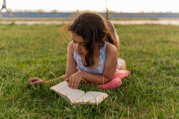 istock Little girl reading book in grass. 2161541782