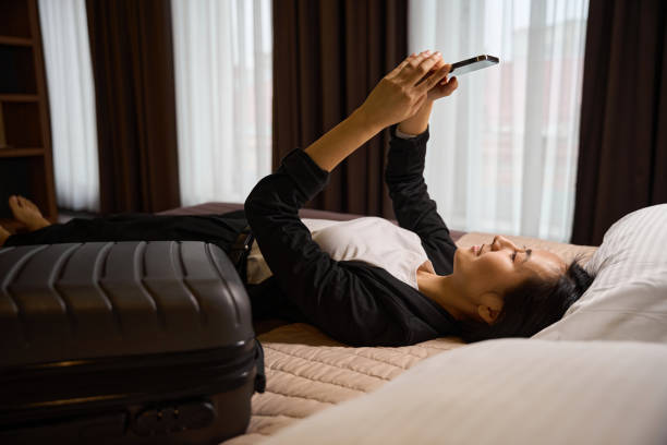 istock Side view Asian woman lying on bed and using smartphone 2161545973