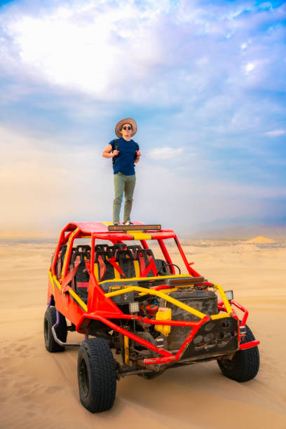 istock Man Standing on Dune Buggy in Huacachina Desert 2161547619