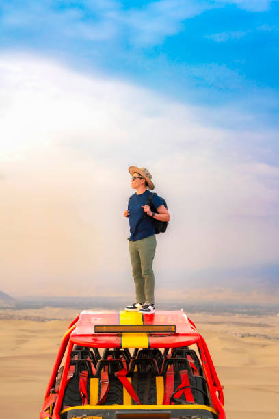 istock Man Standing on Dune Buggy in Huacachina Desert 2161547622