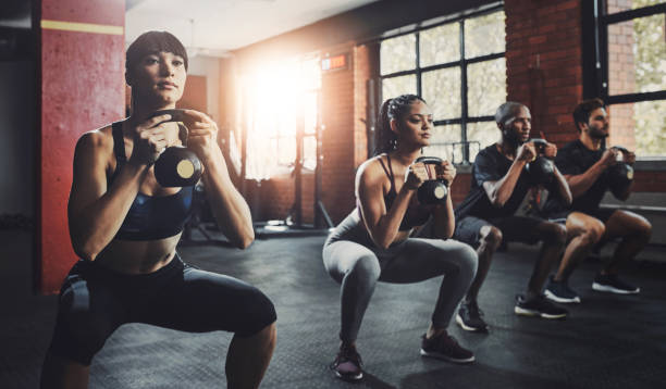 istock Group, exercise and training with kettlebell to squat in class for muscle, wellness or healthy body. Team, fitness and strong people weightlifting for power, bodybuilding and workout together at gym 2161551998