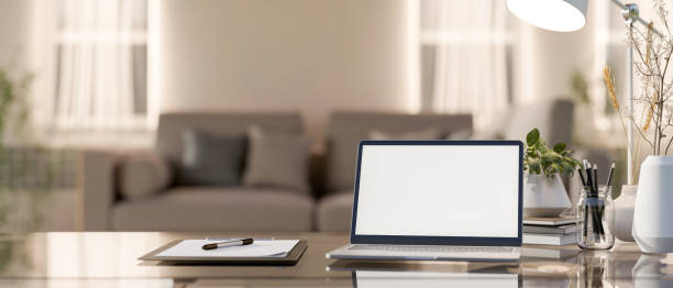 istock A laptop computer with a white-screen mockup on a table in a cozy living room. 2161557780