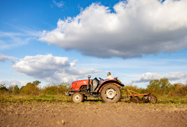 Latin American farmer plowing the land using a tractor - agriculture concepts