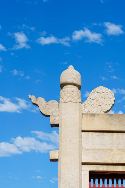 The photo shows the details of the lattice gate before the Circular Mound Altar in the Temple of Heaven in Beijing, China. It is a perfect demonstration of the beauty of ancient Chinese architectures with background of blue sky and white clouds.