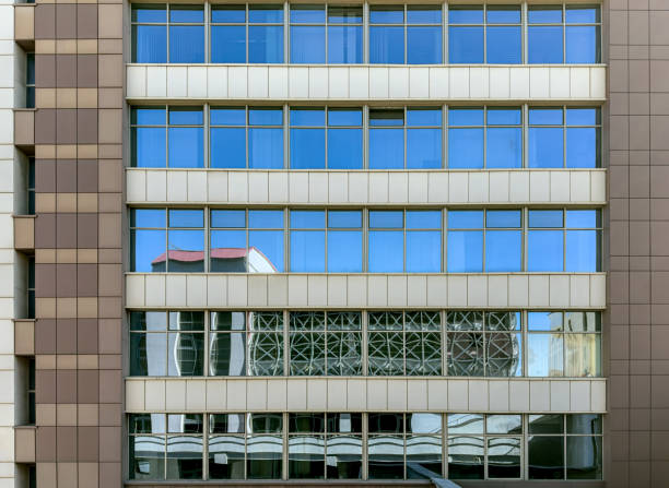 istock modern office building facade. windows reflecting the blue sky and surrounding buildings 2161560603