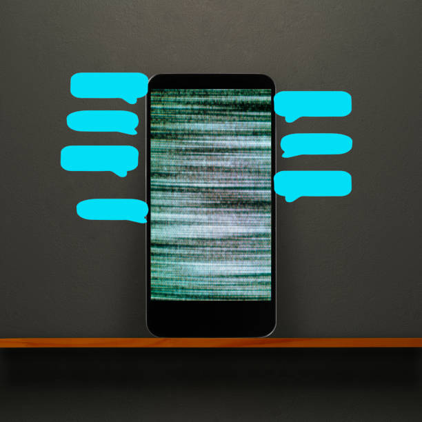 Close-up of grainy screen smart phone with blue speech bubbles on a wooden shelf against dark concrete wall.