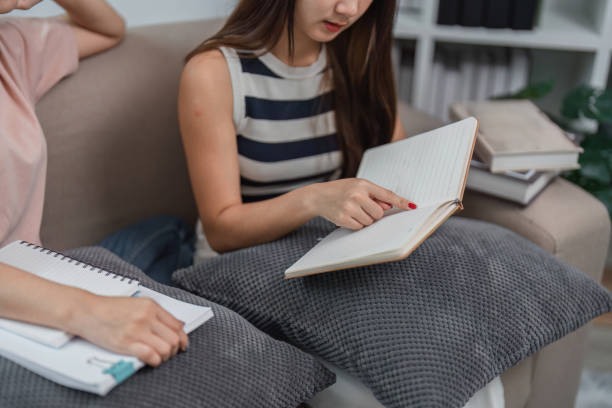 istock Young Female Friends Studying Online and Doing Homework Together on a Comfortable Couch at Home 2161566437