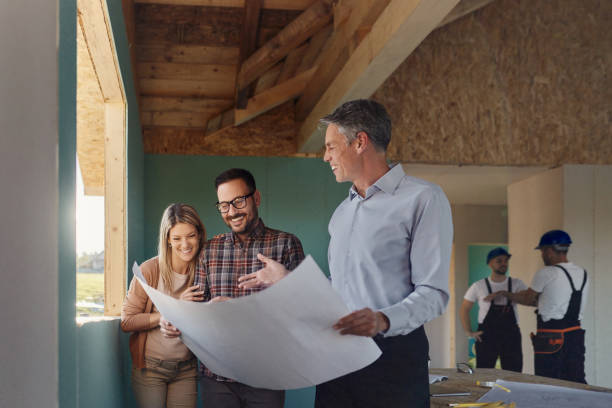 istock Happy male architect examining housing plans with his customers at construction site. 2161572967