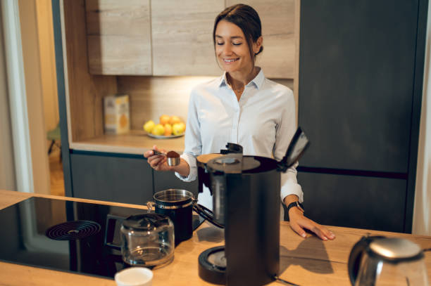 istock Dark-haired young woman in the kitchen making coffee in the coffee machine 2161572985