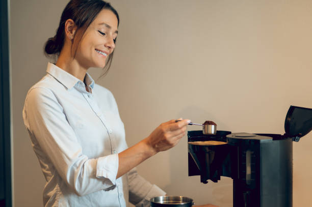 istock Dark-haired young woman in the kitchen making coffee in the coffee machine 2161573070