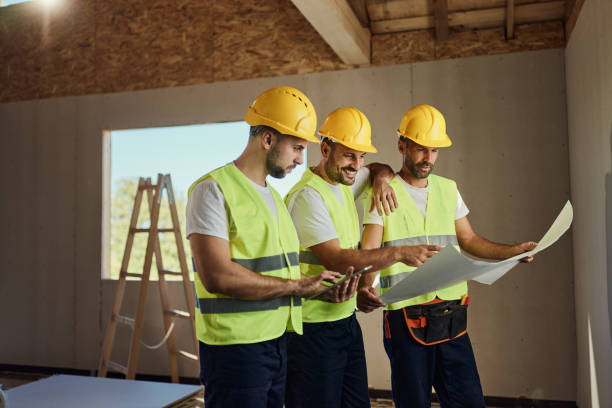 istock Team of manual workers working on touchpad and blueprints at construction site. 2161573212