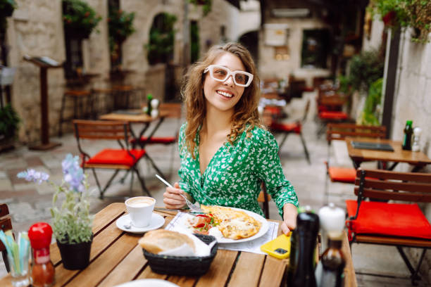 istock Young woman using mobile phone while walks with a bicycle and looks around at beautiful architecture. 2161574038