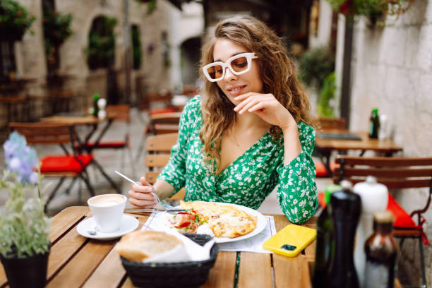 istock Young woman using mobile phone while walks with a bicycle and looks around at beautiful architecture. 2161574055